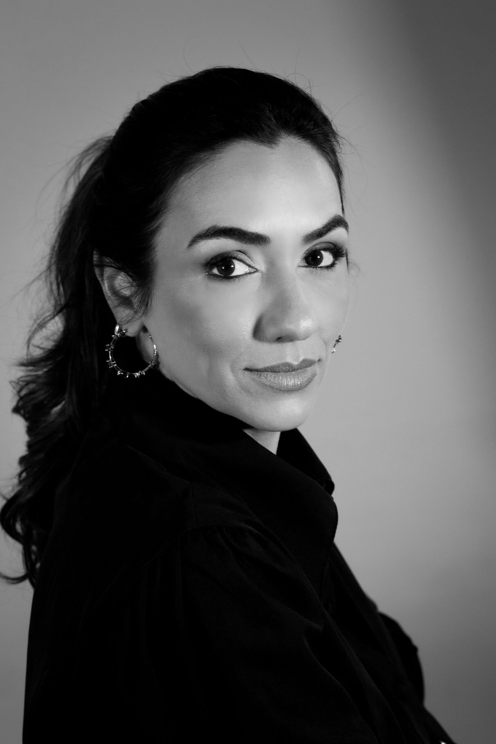 Black and white studio portrait of an elegant woman with a confident look.